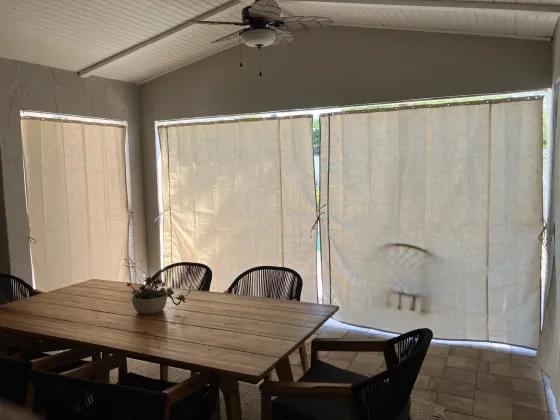 Cream Sunbrella privacy curtains for outdoor dining area in Florida lanai